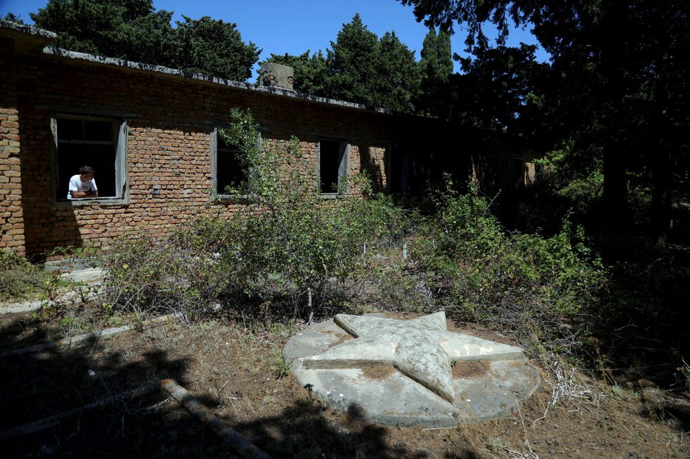 A boy looks through a window of an abandoned school on the island of Sazan, near the Albanian city of Vlore, on Mediterranean coast, on July 30 2024. Ivanka Trump and her husband Jared Kushner want to transform Albania's largest island, and former Cold War Military base built by Albania's former communist rulers. The daughter of former US President want luxury villas to go up on the island of Sazan that for decades served as a garrison with bunkers, fallout shelters and a warren of tunnels designed to withstand a nuclear attack. (Photo by ADNAN BECI / AFP) (Photo by ADNAN BECI/AFP via Getty Images)