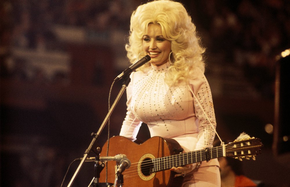 American singer, songwriter and actress Dolly Parton, performs with a guitar, 1976