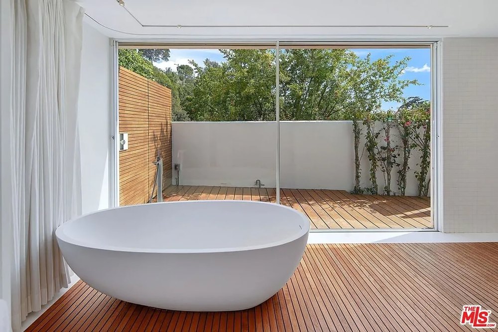 Modern luxury bathroom featuring a freestanding oval soaking tub on a wood floor.