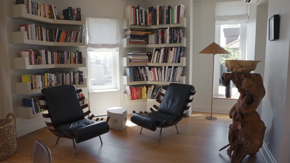 Cozy Library Corner with Wall-Mounted Floating Bookshelves and Black Leather Armchairs